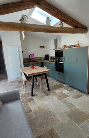 A kitchen with a wooden table, a potted orchid, and a modern oven.