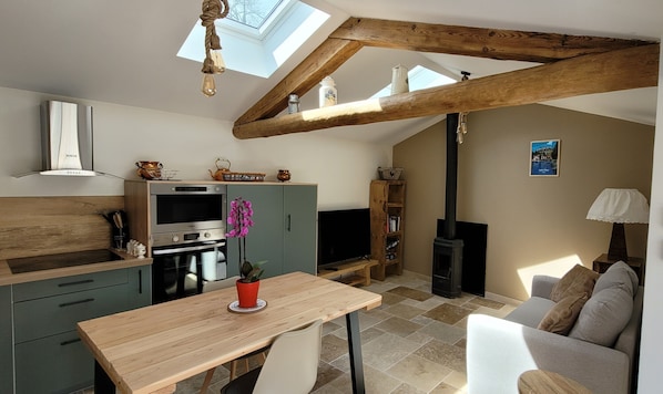 Eine moderne Küche mit Backofen, Esstisch und Fernseher.