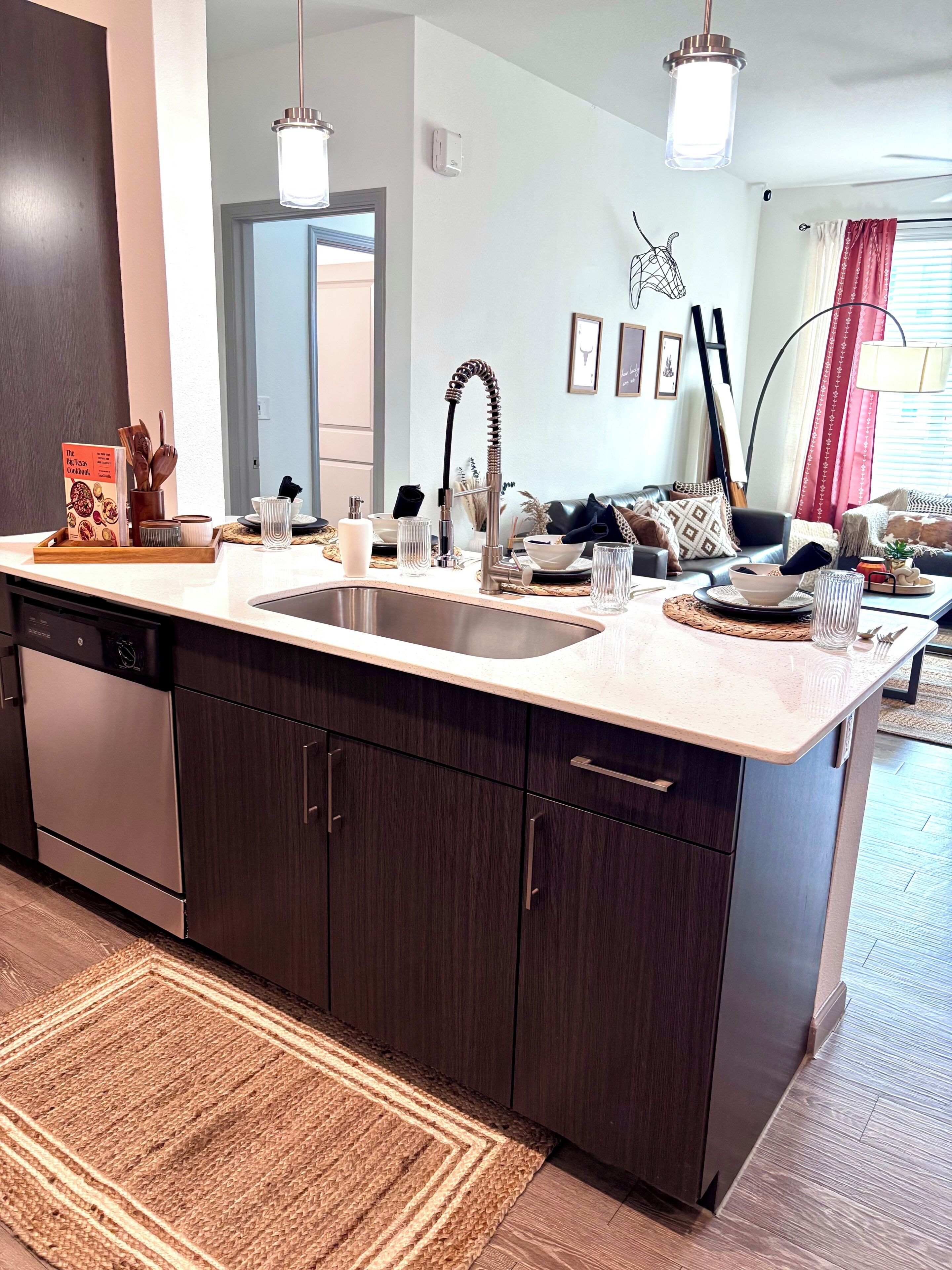 A modern kitchen with a central island, stainless steel appliances, and a dining area with a sofa and table.