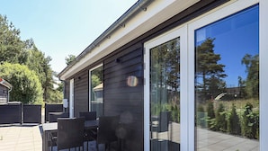 En terrasse med et bord og stole, en skydedør og et metalgitter.