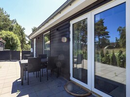 En terrasse med et bord og stole, en skydedør og et metalgitter.