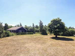 A rural property with a single-story house, a large tree, and a well-maintained lawn. - 5 Star Holiday Home in Vaeggerlose (Vaeggerlose)