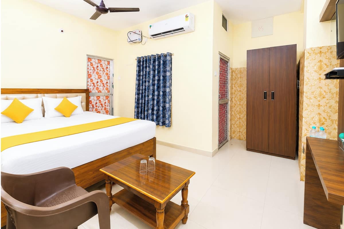 Habitación de hotel con cama, escritorio, silla, unidad de aire acondicionado, ventilador de techo y armario.