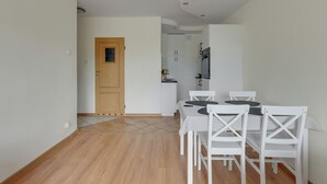 A dining area with a table and chairs, a wooden door, and a kitchen in the background. - Kraszewskiego 21 by Grand Apartments (Sopot)