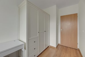 A room with a white wardrobe, a wooden door, and a white desk. - Kraszewskiego 21 by Grand Apartments (Sopot)