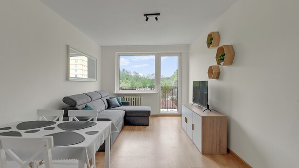 A modern living room with a sofa, dining table, and TV stand. - Kraszewskiego 21 by Grand Apartments (Sopot)