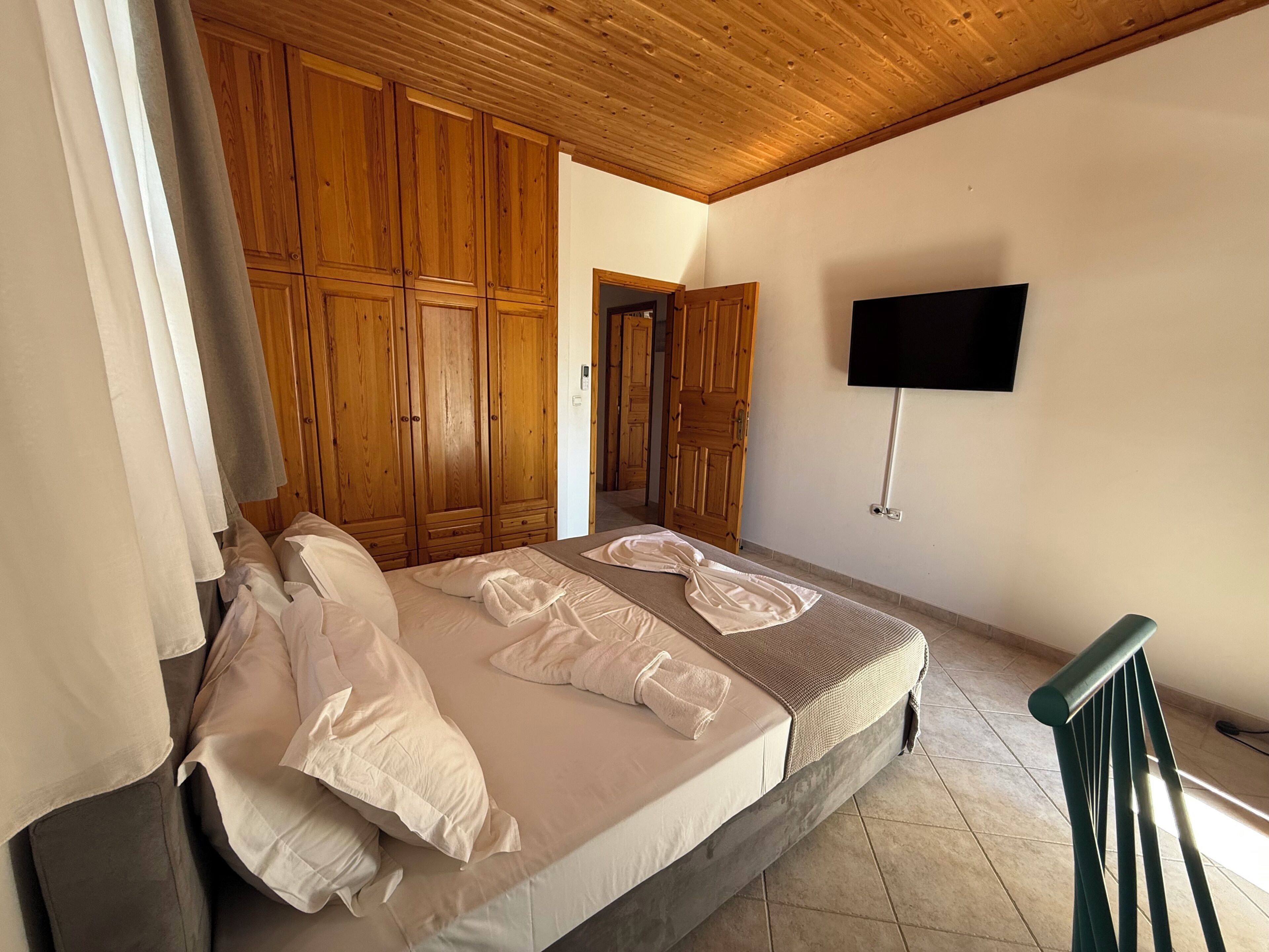 Une chambre à coucher avec un lit, une armoire en bois, une télévision et un escalier.