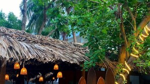 A rustic building with a thatched roof, wooden walls, and a bicycle parked in front. - Fins Arugambay (Arugam Bay)