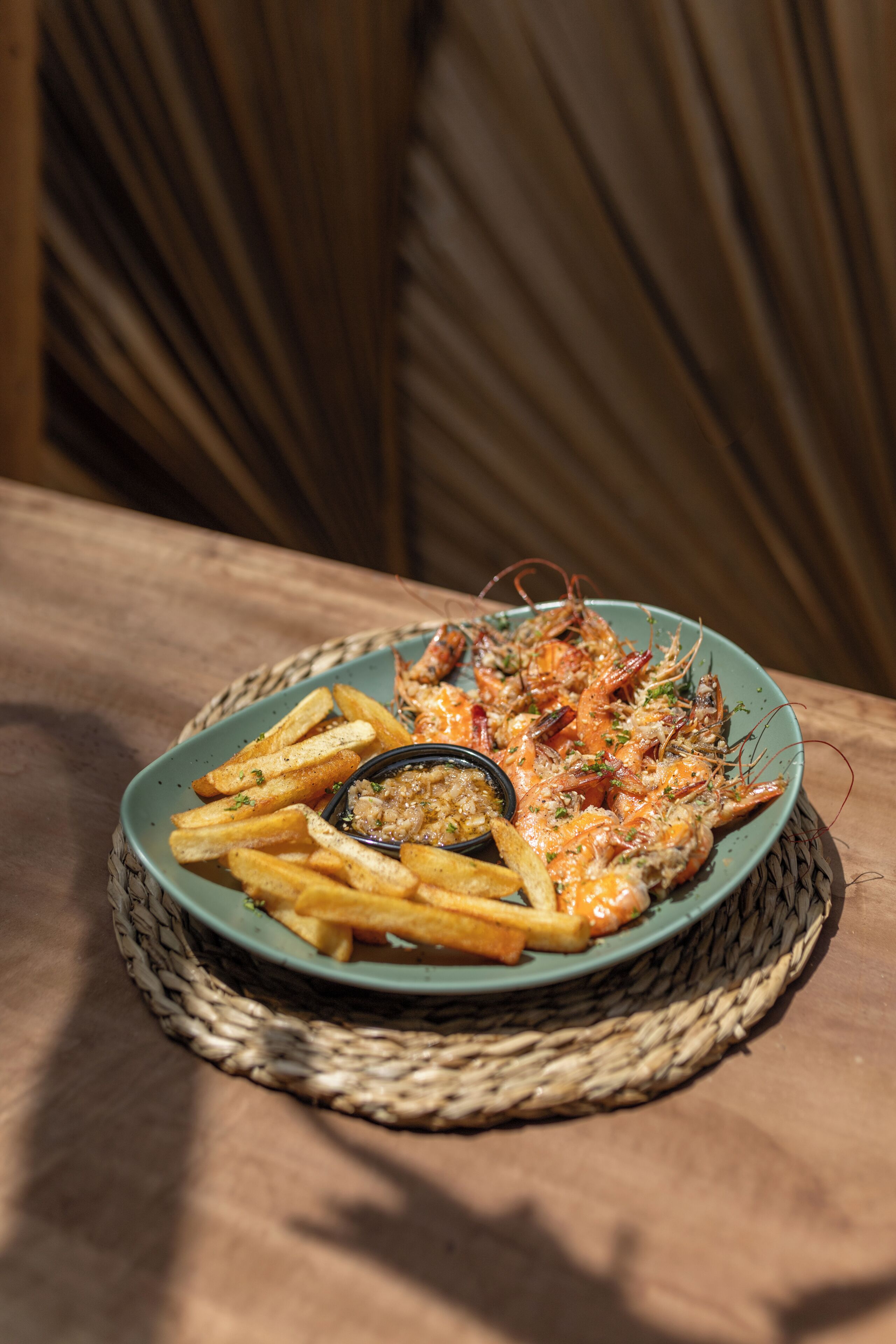 A plate of food with shrimp and fries on a woven placemat.