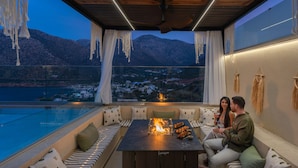 Un área de estar moderna al aire libre con una chimenea, con vistas a un paisaje montañoso.
