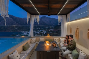 A modern outdoor seating area with a fire feature, overlooking a mountainous landscape. - Azur Blue luxury villa , great views near the beach (Bali)