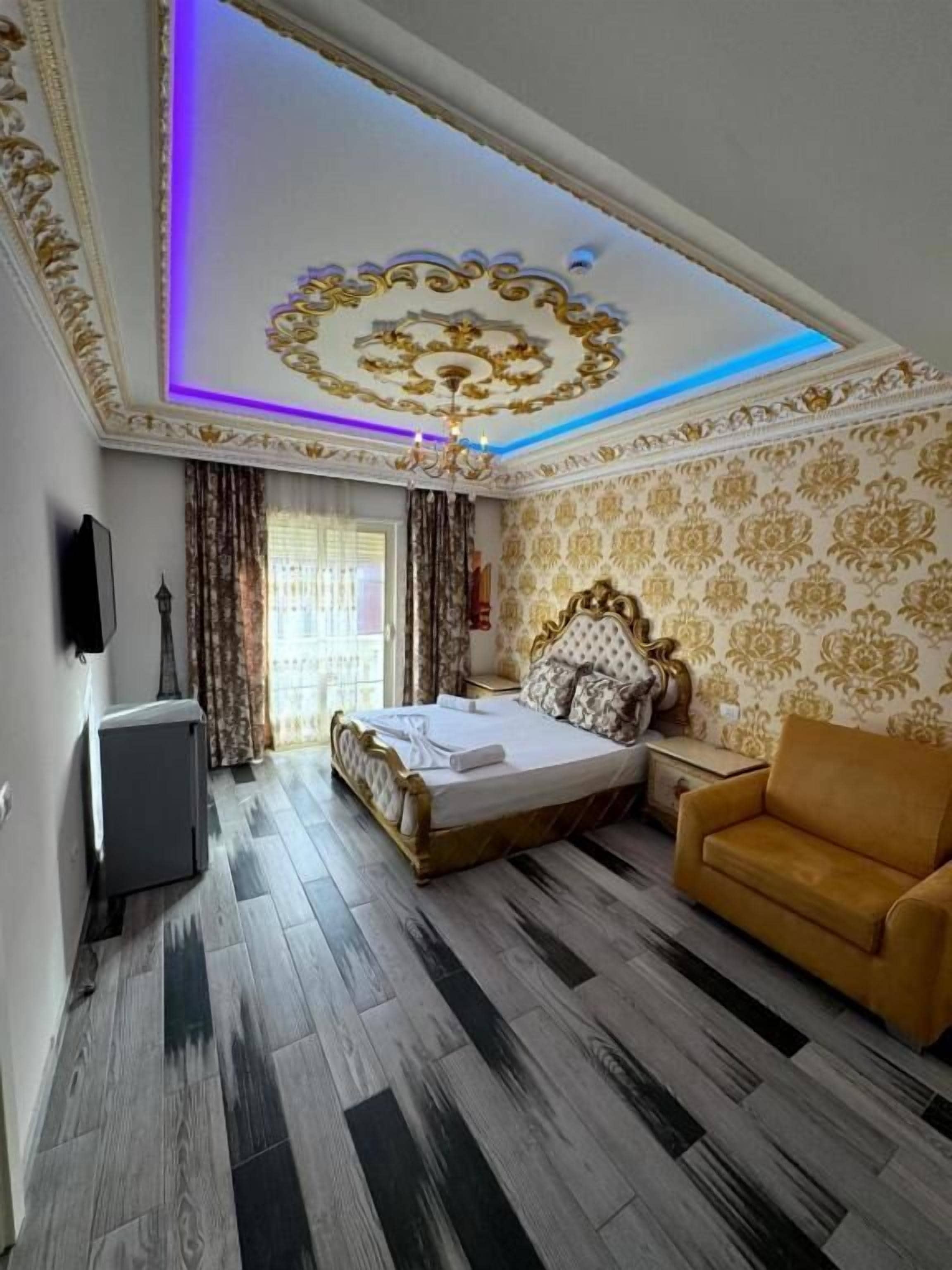 Un dormitorio con una cama, un sofá, un televisor y un techo con diseños decorativos.