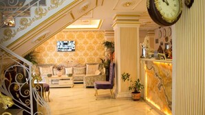 A hotel lobby with a staircase, a reception desk, a sofa set, and a large wall clock. - Hotel Antalya Beach Durres (Durrës)