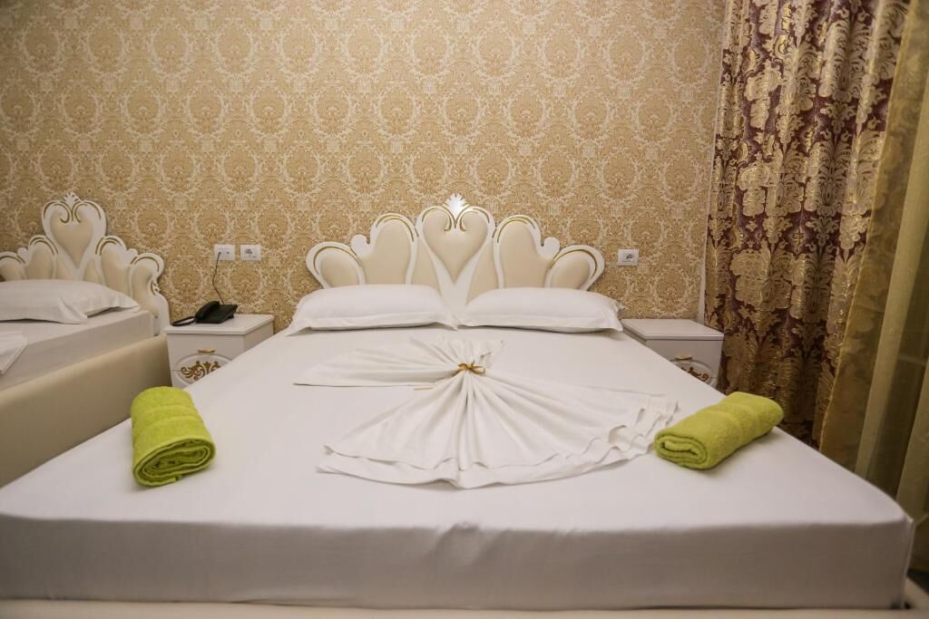 A hotel room with a large bed, two bedside tables, and a patterned wallpaper.