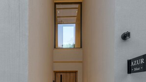 A hallway with a wooden floor, a door, a potted plant, and a sign that reads 'AZUR blue'. - Azur Blue Luxury Villa (Mylopotamos)