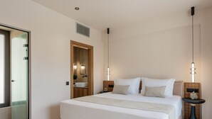 A modern hotel room with a large bed, bedside tables, a built-in sink, and pendant lighting. - Azur Blue Luxury Villa (Mylopotamos)