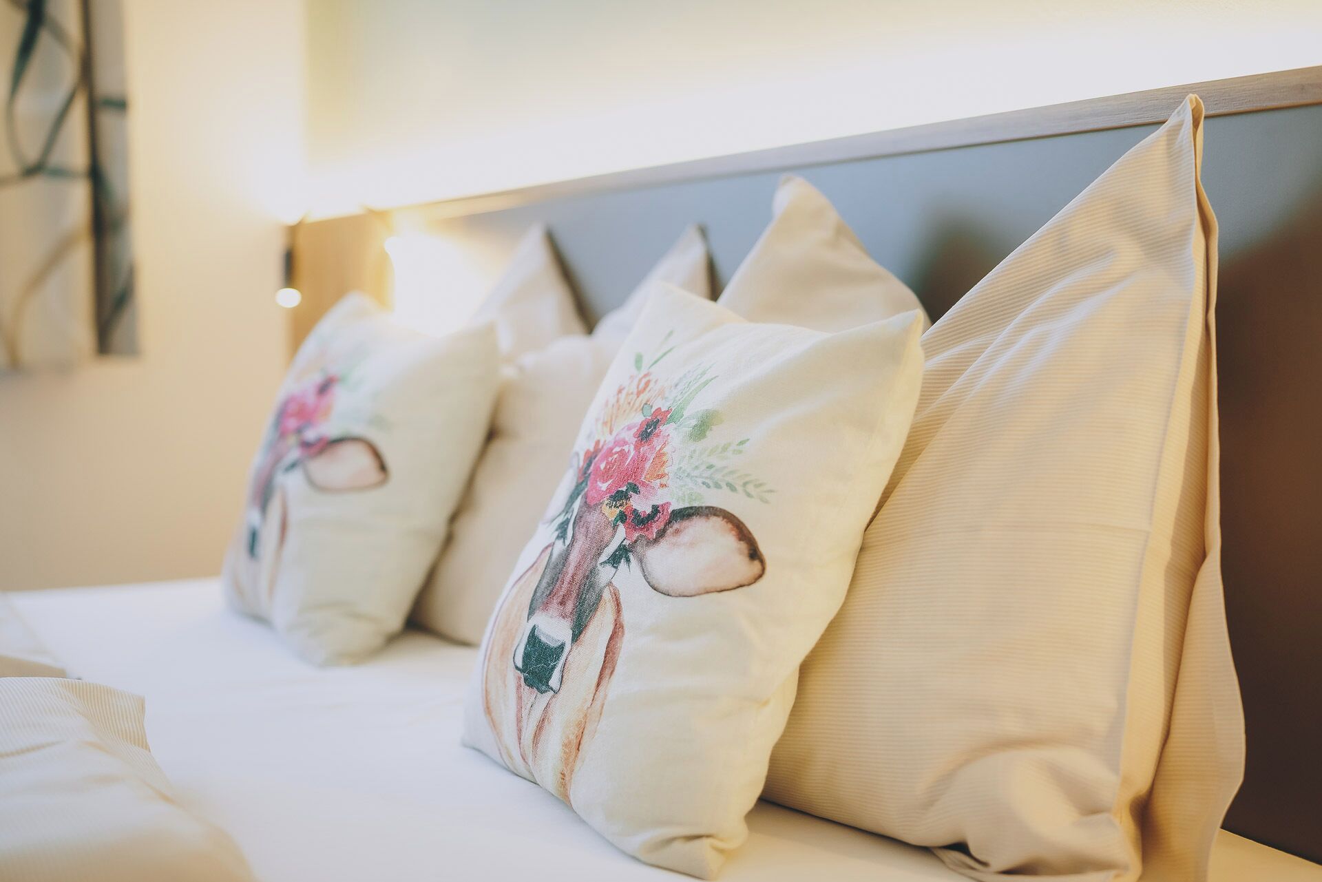 A bed with pillows featuring floral embroidery and a headboard.