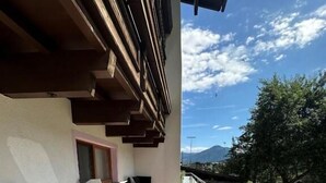 A balcony with a wooden floor, metal railings, and a seating area with chairs and a sofa. - Pension Monika (Kaprun)