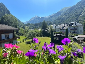 A mountain landscape with a hotel featuring multiple buildings, a wooden house, and a well-maintained lawn.