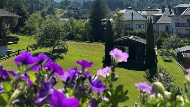 A mountainous landscape with houses, a clear sky, and purple flowers in the foreground. - Pension Monika (Kaprun)