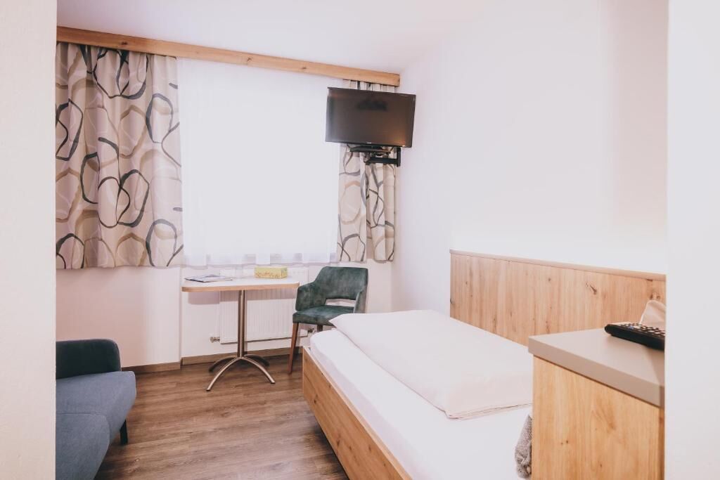Ein Schlafzimmer mit Bett, Schreibtisch, Stuhl, Fernseher und einem Holzkopfteil.