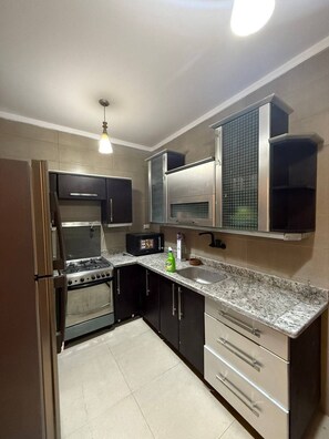 A kitchen with a stove, oven, microwave, and a sink. - Basuiony hotel  (Giza)