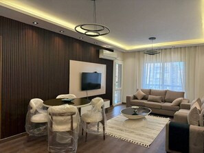 Een moderne woonkamer met een flatscreen televisie, een ronde salontafel en een bank.