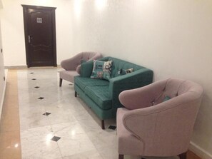 A hallway with a teal sofa, two armchairs, and a dark wooden door labeled 'G5'. - Basuiony hotel  (Giza)