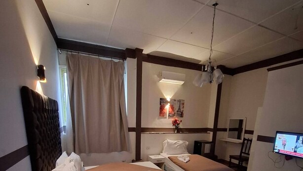 Une chambre d’hôtel avec deux lits, un bureau, une chaise, une télévision et une fenêtre avec des rideaux.