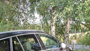 A black car parked on a road with a charging cable connected to it. - Les Gites du Bois de Chelles (La Chapelle-Geneste)
