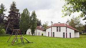 A two-story building with a red roof, surrounded by a grassy lawn and trees. - Les Gites du Bois de Chelles (La Chapelle-Geneste)