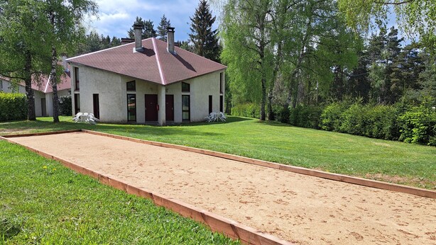 A house with a red roof, a front lawn, and a sand court. - Les Gites du Bois de Chelles (La Chapelle-Geneste)