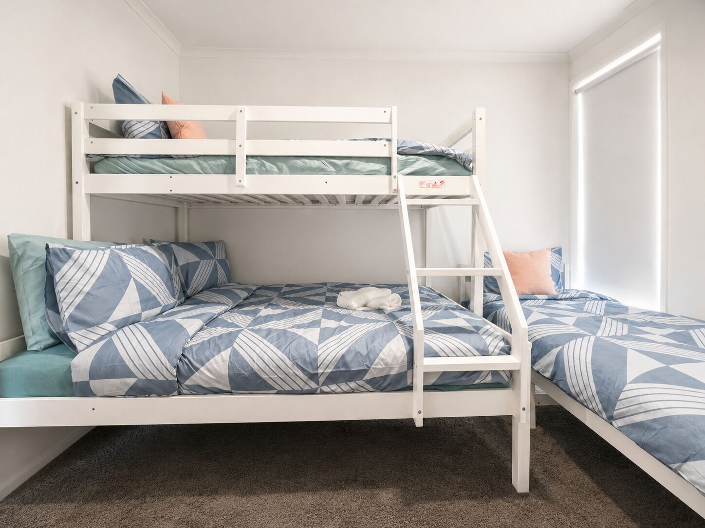 A bunk bed with a ladder, a pillow, and a blanket.