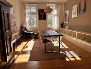 A room with a wooden table, chairs, a rug, a radiator, and artwork on the walls. - Central apartment, 4 beds, fully equipped kitchen, free parking spaces (Berlin)