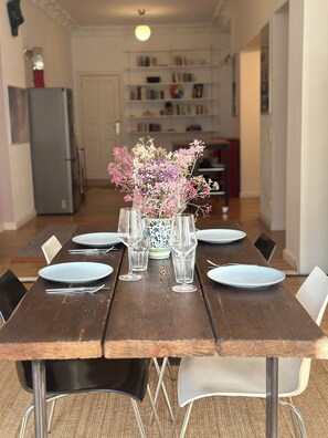 A dining table set with plates, glasses, and cutlery, with a vase of flowers in the center. - Central apartment, 4 beds, fully equipped kitchen, free parking spaces (Berlin)