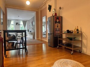 A modern kitchen with a stainless steel refrigerator, a cart with kitchenware, and a woven ottoman. - Central apartment, 4 beds, fully equipped kitchen, free parking spaces (Berlin)