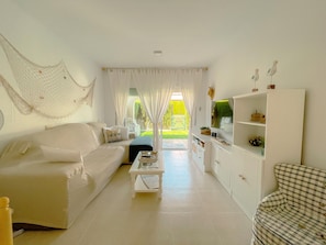 Ein Wohnzimmer mit einer Couch, einem Couchtisch, einem Schrank und Blick auf einen Garten.