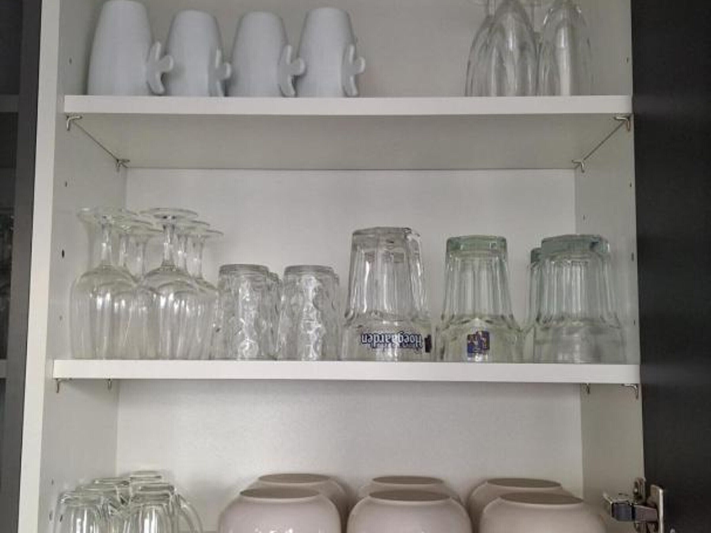 Uno scaffale bianco con diversi bicchieri e oggetti in ceramica.