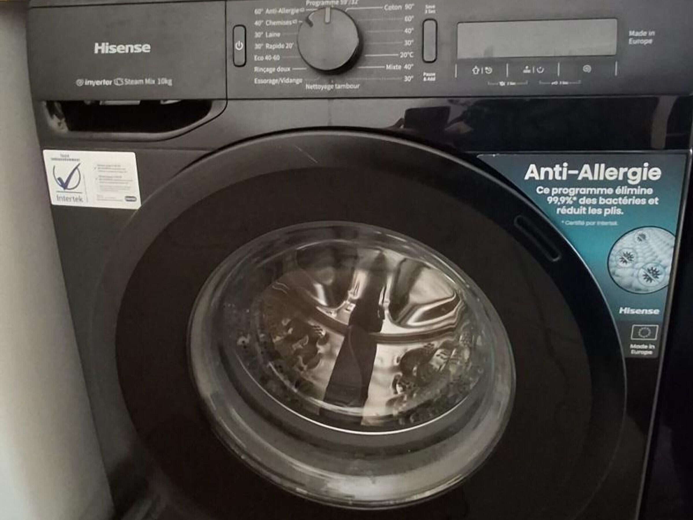A Hisense washing machine with a transparent door, a control panel with various settings, and an 'Anti-Allergy' program label.