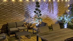 An outdoor patio with a brick wall, string lights, and seating. - Charming lodging near Lille - 2 guests (SAINGHIN EN WEPPES)