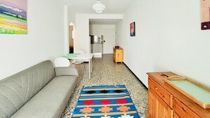 Un pasillo estrecho con un sofá, una mesa, un aparador de madera y una alfombra colorida.