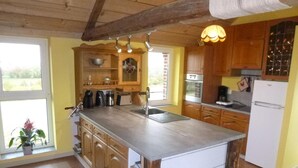 Une cuisine avec des meubles de rangement en bois, un îlot central, un évier et un réfrigérateur.