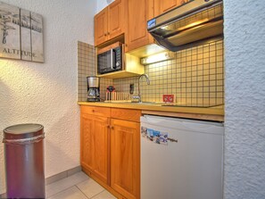 A compact kitchen with wooden cabinets, a microwave, a coffee maker, and a refrigerator. - Charming apartment in Morzine - 4 guests (Morzine)