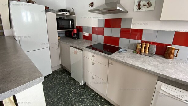 A compact kitchen with a refrigerator, microwave, stove, and a red and grey tiled backsplash. - Ideal duplex apartment, village centre - 8 guests (Les Angles)