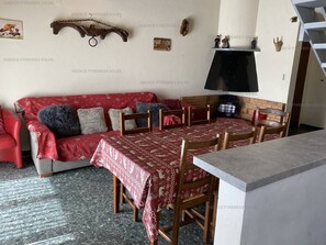 Ein gemütliches Wohnzimmer mit einem roten Sofa, Holzstühlen, einem Esstisch und einem Kamin.
