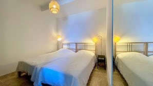 Een slaapkamer met twee bedden, een hanglamp en bedlampjes.