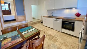 Een moderne keuken met witte kastjes, een vaatwasser, een oven en een eettafel met stoelen.