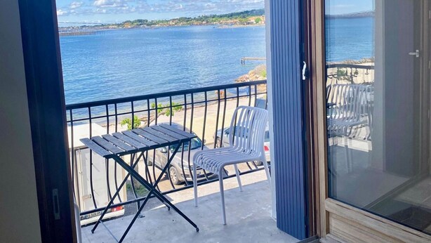 Een balkon met uitzicht op zee, een tafel en twee stoelen.
