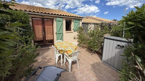 Eine Terrasse mit Tisch und Stühlen, ein kleines Gartenhaus und ein Gartenbereich mit Pflanzen.