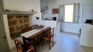 Una cuina amb taula de dinar, cadires, una làmpada penjant i una finestra amb vistes.